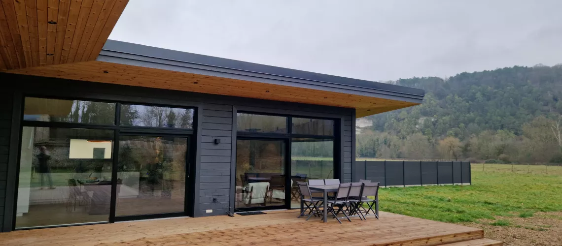 Maison en madrier de plain-pied avec larges terrasses couvertes, avec de grandes parties vitrées