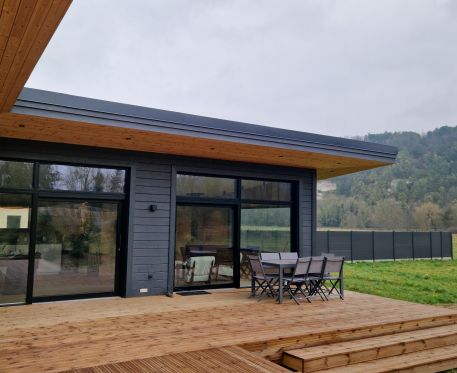 Maison en madrier de plain-pied avec larges terrasses couvertes, avec de grandes parties vitrées